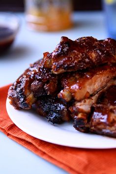 some meat is sitting on a white plate with an orange napkin and blue water in the background