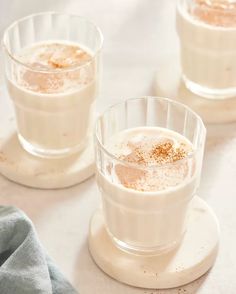 three glasses filled with liquid sitting on top of a table