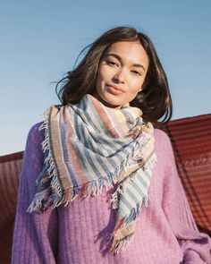 a woman wearing a pink sweater and striped scarf