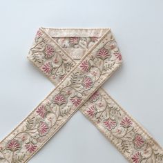 an embroidered piece of cloth with flowers and leaves on the edge is laying on a white surface