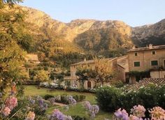 an old house surrounded by flowers and mountains