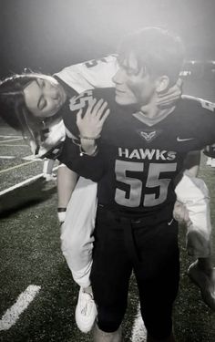 a football player is hugging his girlfriend on the field