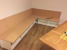 an empty room with wooden flooring and white bench tops on the wall, next to a workbench that is being built into the wall