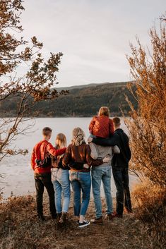 a group of people standing on top of a hill next to a body of water