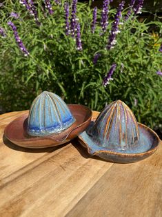 two small bowls sitting on top of a wooden table next to purple and white flowers