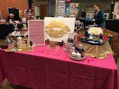 a pink table topped with lots of beauty products and cosmetics on top of a purple table cloth