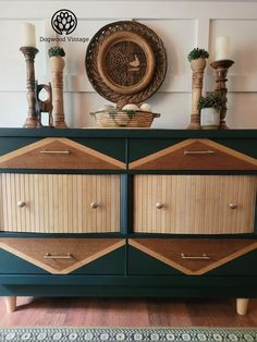 a green dresser with wooden drawers and decorative items on top