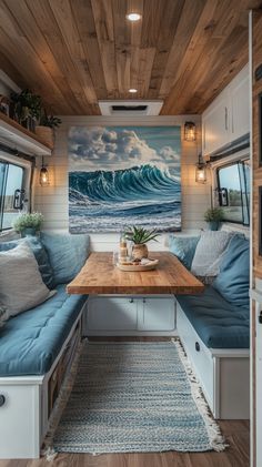 the inside of a recreational vehicle with a couch and table in front of an ocean painting