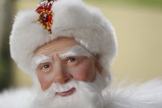 an old man dressed as santa claus with white hair and beard wearing a red jeweled headpiece