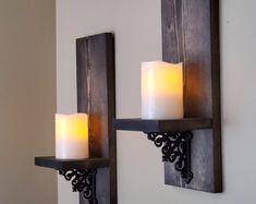 two candles are lit on the wall next to each other in front of a candle holder