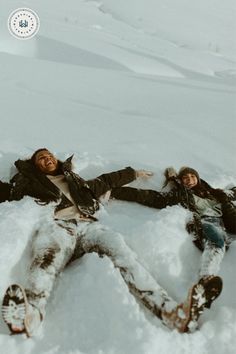 two people are laying in the snow together