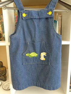 Toddler 1970's Blue Denim Sum Dress/Jumper by Tiny Folks 50 % Polyester 50% Cotton 6 1/4 X 5 Inch Front Pocket with Rabbit & Turtle Appliques 4 Yellow Strap Buttons MEASUREMENTS (in inches): Shoulder to Shoulder (back): 8 Chest: 24 Waist: 26 Hips: 28 Side Length (armpit to hem): 12 Arm Length (armpit to cuff): Sleeveless Neck Opening: 20 Square / 1 Inch Straps Bib Top to Hem: 17 / 1 Inch Hem INTERNATIONAL CUSTOMER?? Please email for Shipping Info Retro Cotton Denim Dress With Pockets, Vintage Denim Blue Denim Dress With Pockets, Vintage Blue Shortalls, Vintage Medium Wash Denim Dress With Pockets, Vintage Blue Cotton Shortalls, Vintage Denim Blue Cotton Shortalls, Blue Vintage Cotton Shortalls, Vintage Blue Denim Dress With Pockets, Vintage Blue Sleeveless Denim Dress