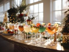 many different types of drinks are lined up on a table in front of a christmas tree