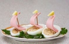 three deviled eggs with pink sails are on a plate