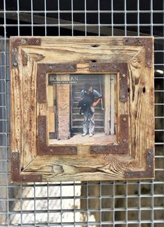 a wooden frame hanging on a wire fence with an image of a man climbing up the stairs