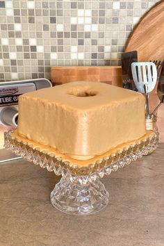 a cake sitting on top of a glass plate next to a knife and spatula