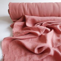 an unmade bed with pink sheets and pillows