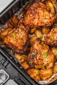 chicken and potatoes in an air fryer with parsley on the top, ready to be cooked