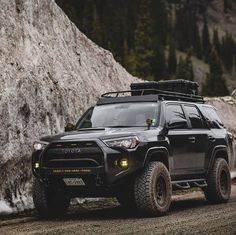 a black toyota 4x4 is parked in front of a large rock