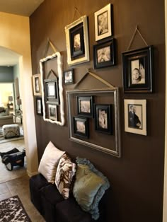 a living room filled with pictures and frames on the wall next to a couch in front of a doorway