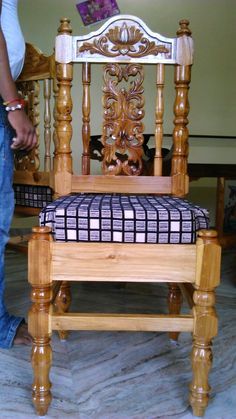 a person standing next to a wooden chair with a checkered seat cover on it