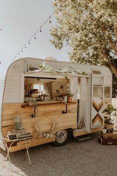 an old camper converted into a mobile bar with lights strung from the roof and windows