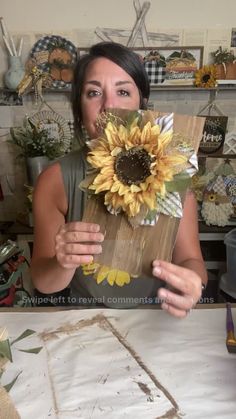 a woman holding up a paper bag with a sunflower on it in front of her face