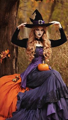 a woman dressed as a witch sitting on top of a tree