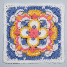 a crocheted square with an intricate flower design on the center and sides in blue, yellow, pink, white and orange