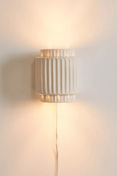 a white wall lamp with dim lights on it's side against a white wall