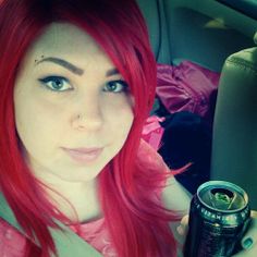 a woman with red hair holding a can of soda