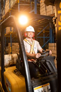 a man sitting on top of a forklift in a warehouse