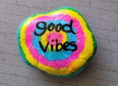 a colorful rock with the words good vibes painted on it sitting on a table