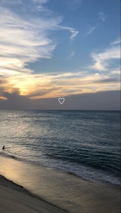 the sun is setting over the ocean with people walking on the beach and in the water