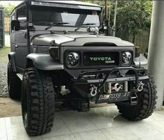 the front end of a black toyota truck parked in a parking lot with its lights on