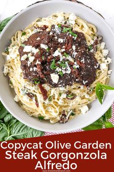 a white bowl filled with pasta covered in meat and cheese on top of green leaves