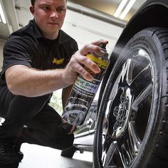 a man is working on a tire with a spray bottle and some tires in front of him