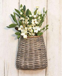 a wicker basket with flowers in it hanging on a wall