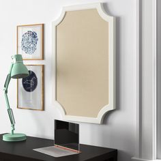 a desk with a lamp and a mirror on it next to a wall mounted clock