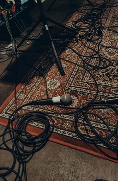 an old microphone is laying on the floor next to some wires and cords that are plugged in