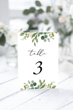 a table number card with greenery on it