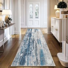 a blue and white area rug in the middle of a wooden floored entryway