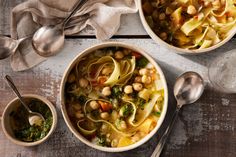 two bowls filled with soup next to spoons and silverware on a wooden table