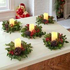 christmas wreaths with lit candles on a table