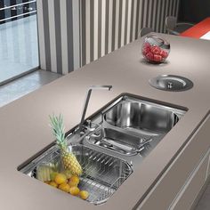 a stainless steel sink with a pineapple in the middle and other fruit on the counter