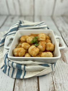 a white dish filled with tater tots on top of a blue and white towel