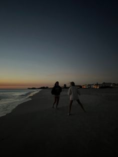 two people walking on the beach at night