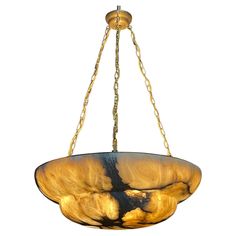 a chandelier hanging from the ceiling with gold and black glass in front of a white background