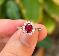 a close up of a person holding a ring with a red stone