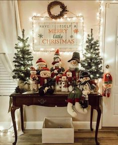 a group of snowmen sitting on top of a wooden table in front of a christmas sign